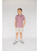 Young boy wearing a patterned shirt and shorts on a plain background