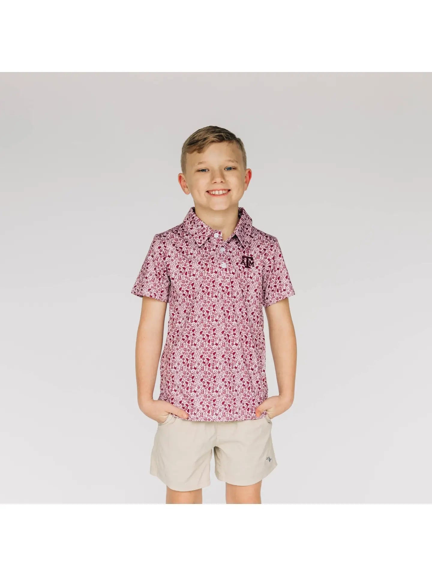 Young boy wearing a patterned shirt and beige shorts on a white background