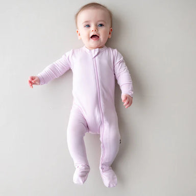 Baby wearing a purple onesie on a plain background