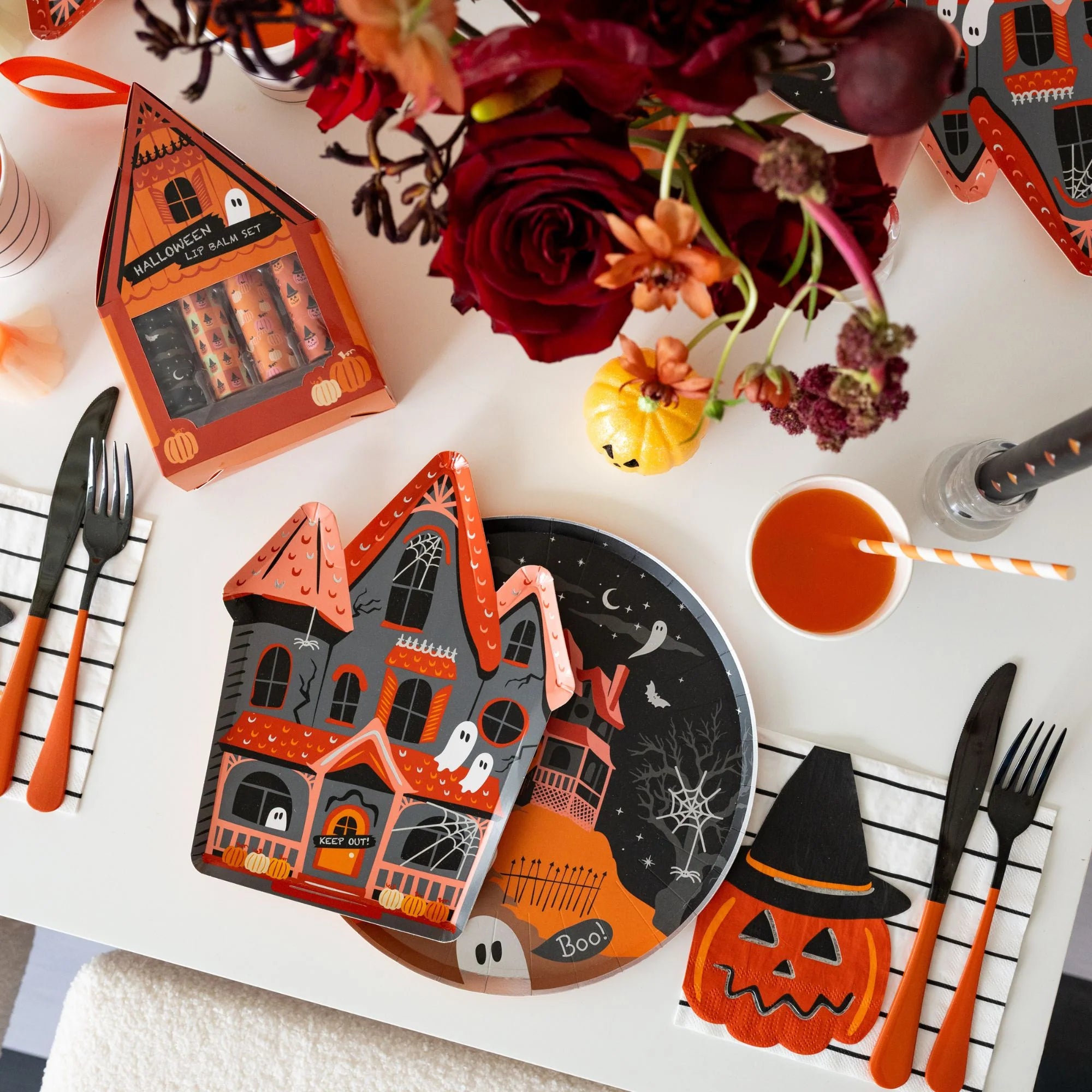 Halloween-themed table setting with haunted house plate, cutlery, and decorative items.