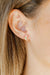 Close-up of an ear wearing a colorful earring with blonde hair.