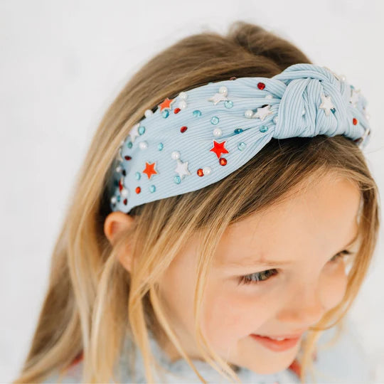 Child wearing a decorative headband with stars and beads on a plain background