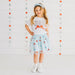 Young girl wearing a 'USA' t-shirt and star-patterned skirt against a star-patterned background