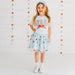 Young girl wearing a 'USA' t-shirt and floral skirt against a star-patterned background
