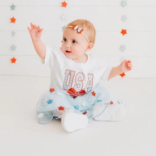 Baby wearing a 'USA' shirt with a star-themed background
