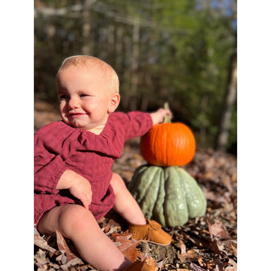 baby girl sitting up wearing burgundy long sleeve bubble with gathered waist and at the neck