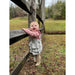 little girl wearing long sleeve rose colored onesie with ruffled sleeve