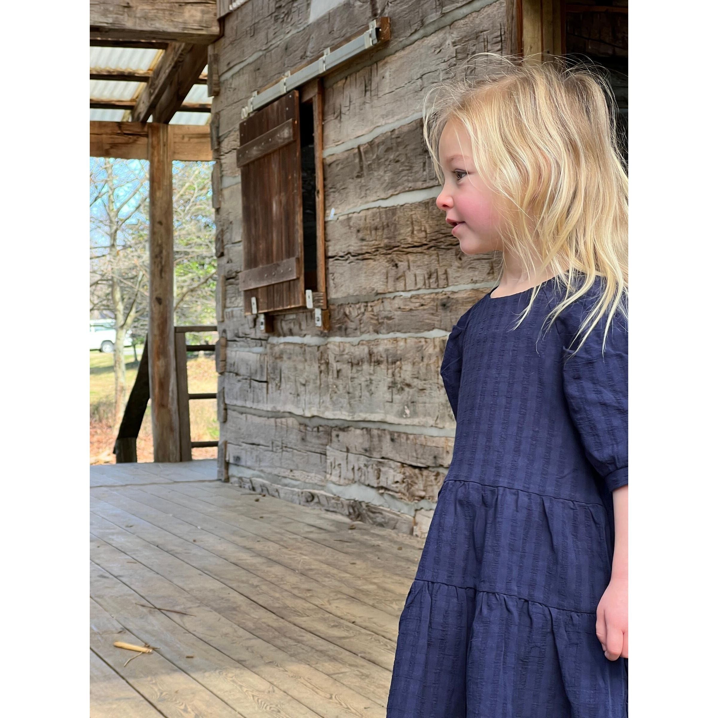 Little girl wearing navy multi-layered dress with short sleeves.