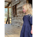 Little girl wearing navy multi-layered dress with short sleeves.