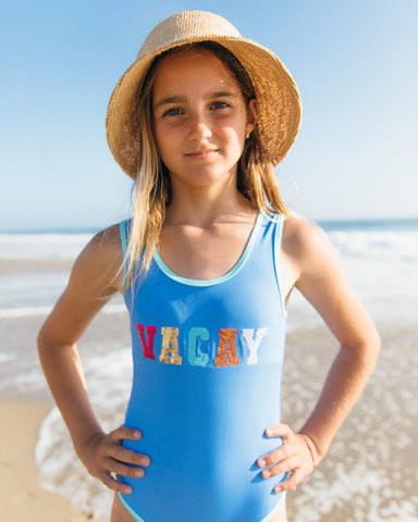 Blue girls swimsuit with Vacay sparkle across the front