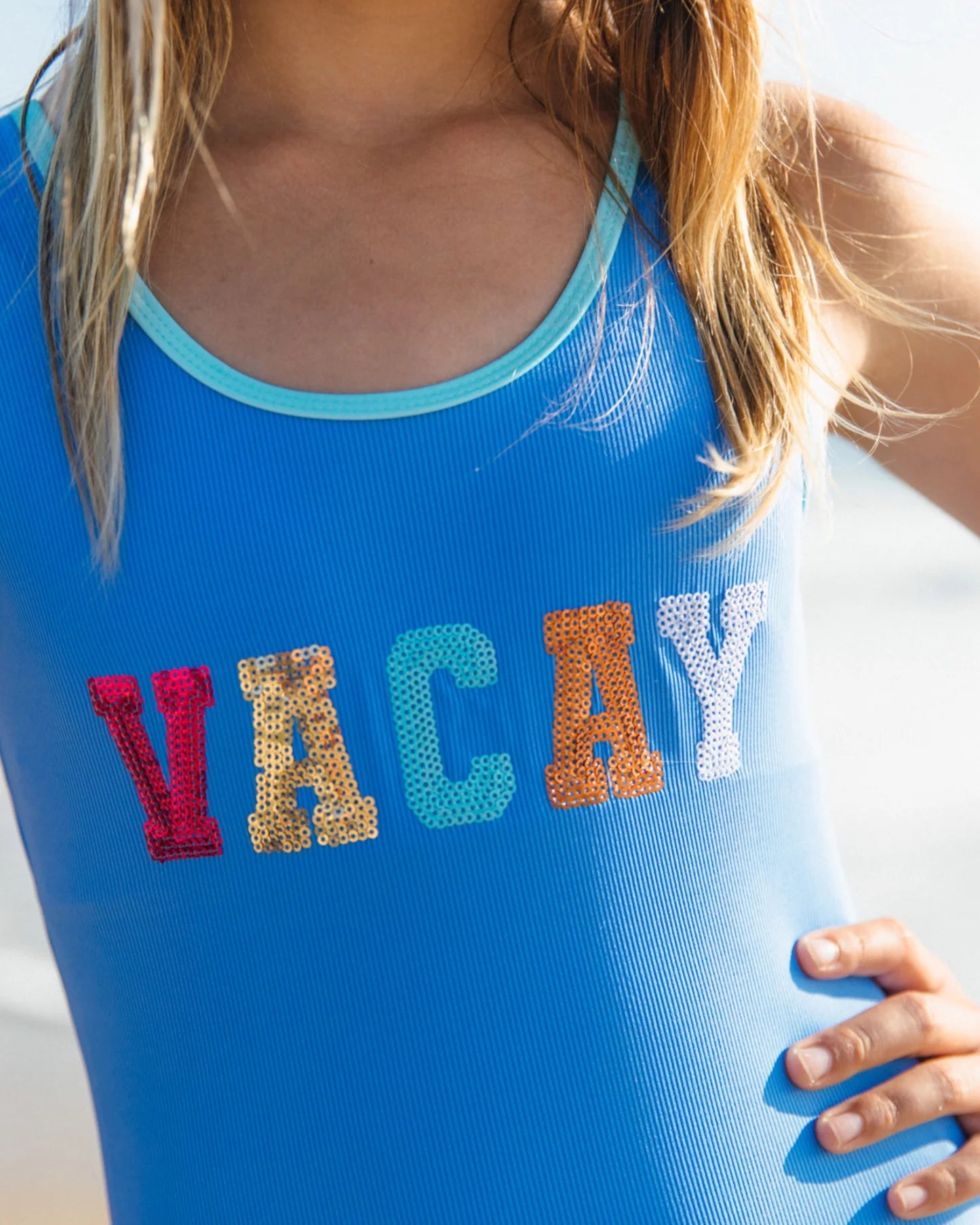Blue girls swimsuit with Vacay sparkle across the front