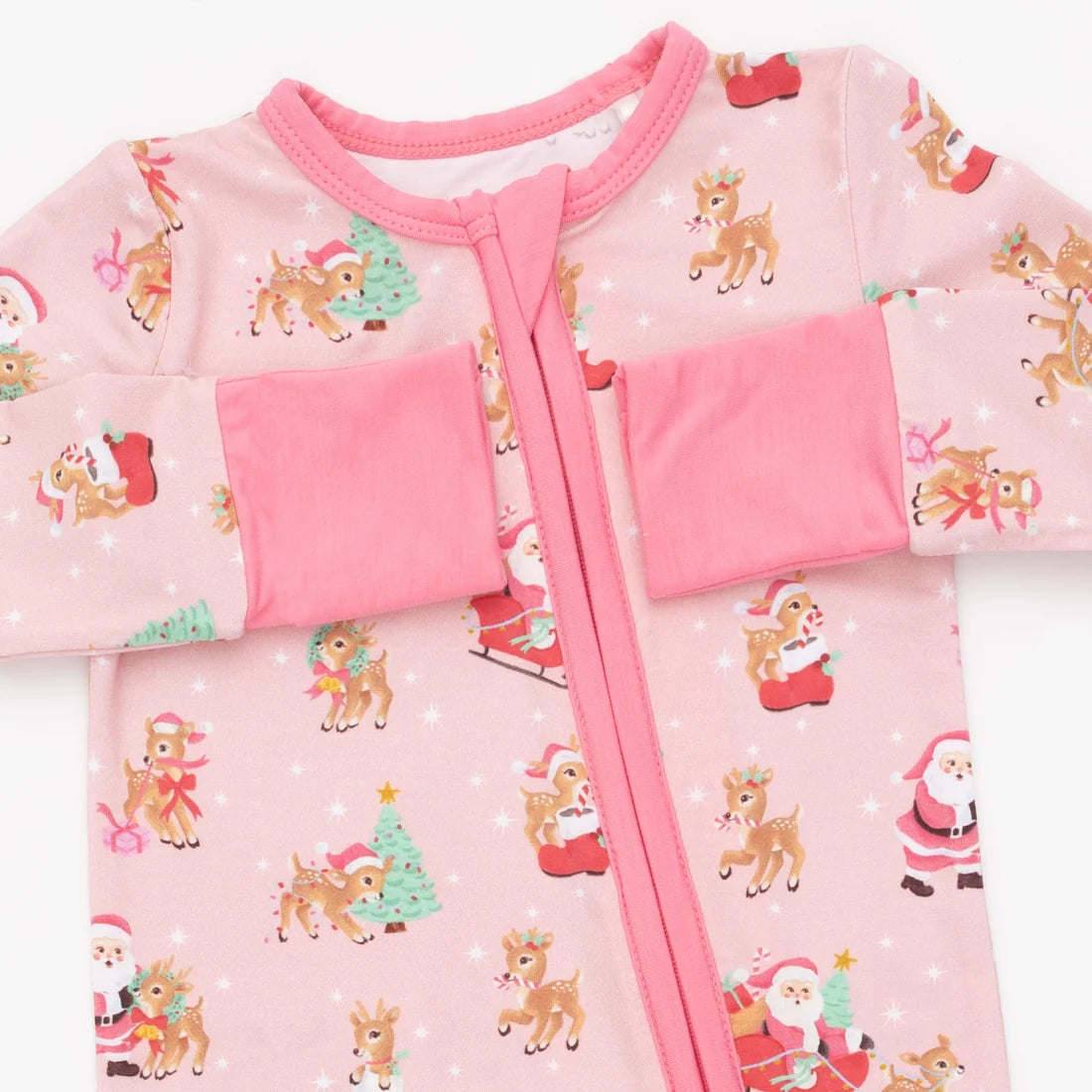A baby long-sleeve sleep sack in light pink with a festive holiday print of Santa Claus, reindeer, and Christmas trees, featuring a pink zipper and matching pink cuffs.
