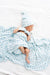 Newborn baby wrapped in a blue checkered blanket and hat on a white background