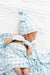 Newborn baby swaddled in blue and white checkered blanket with matching hat.