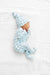 Newborn baby wearing a blue checkered outfit and hat, lying on a white textured surface.