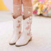 White cowboy boots with pink bows worn by a child on a light background