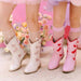 Children's white and pink cowboy boots with decorative elements on a floral background.