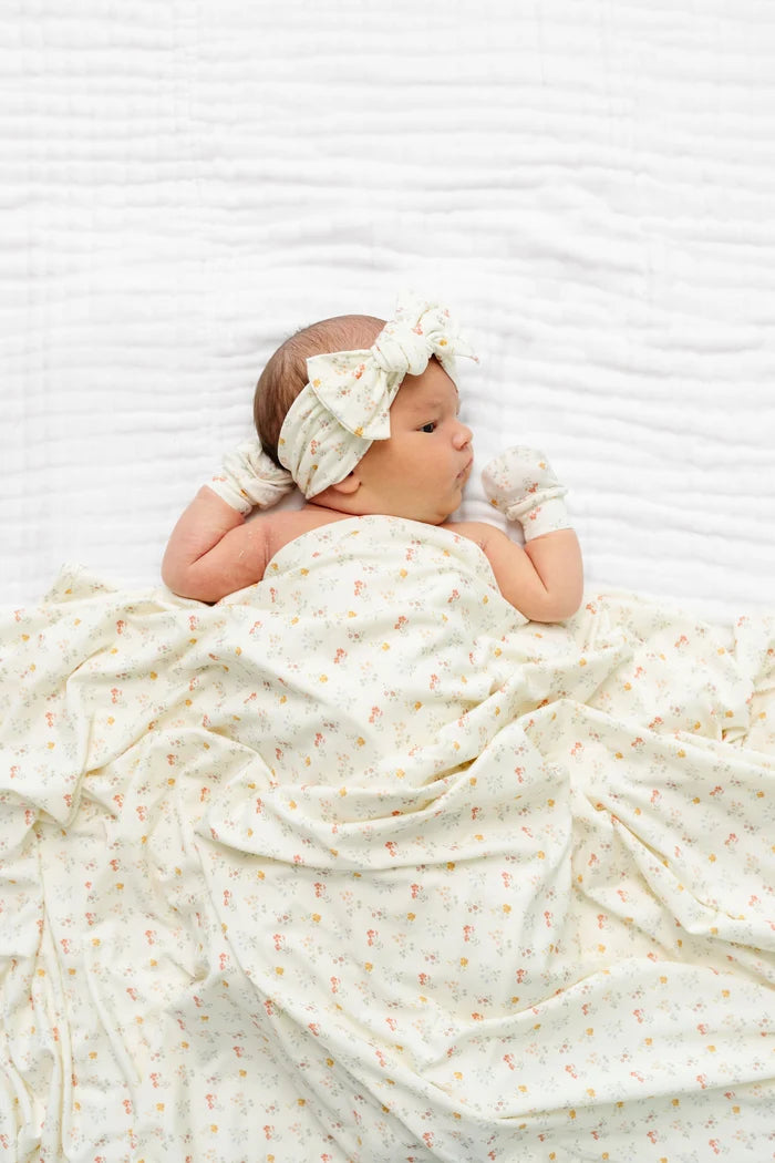 Newborn baby wrapped in a white blanket with a bow on a white background