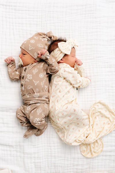 Two babies in matching outfits lying on a white textured surface