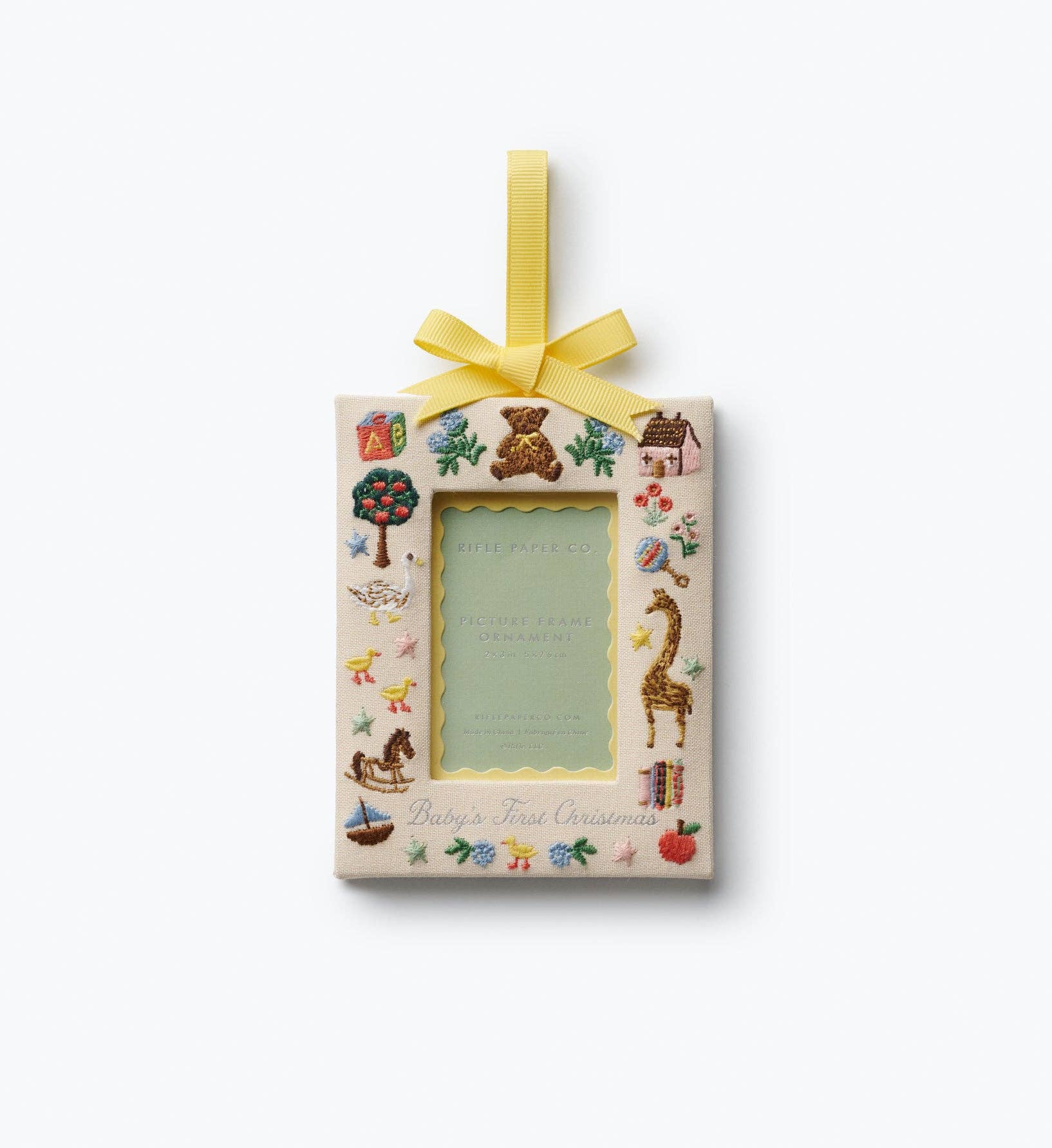 Rifle Paper Co. Baby's First Christmas photo frame ornament with nursery motifs and a yellow ribbon around a 2x3 inch photo opening