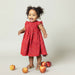 baby girl wearing red sleeveless dress with smocking at the chest and tiny white rose print
