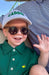 Child wearing a green shirt with a logo, sunglasses, and a cap with 'CADDIE' text.