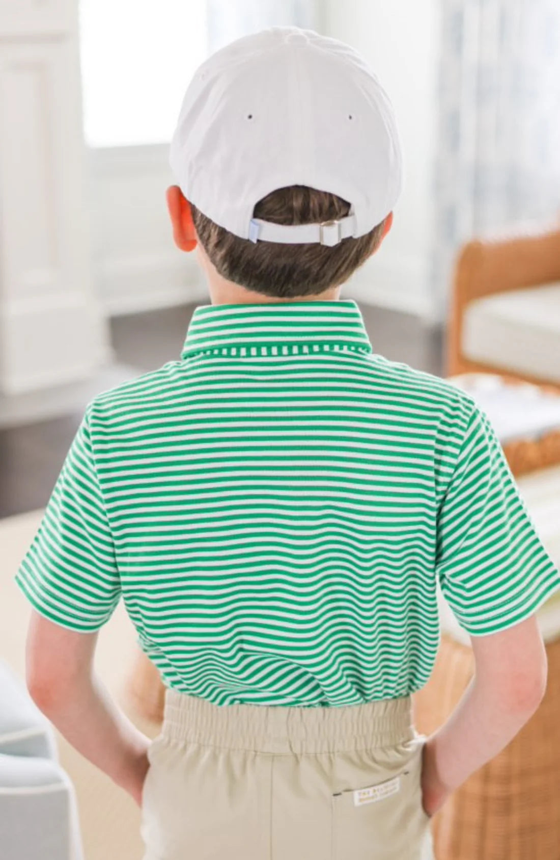 Child wearing a green and white striped shirt and beige pants indoors.