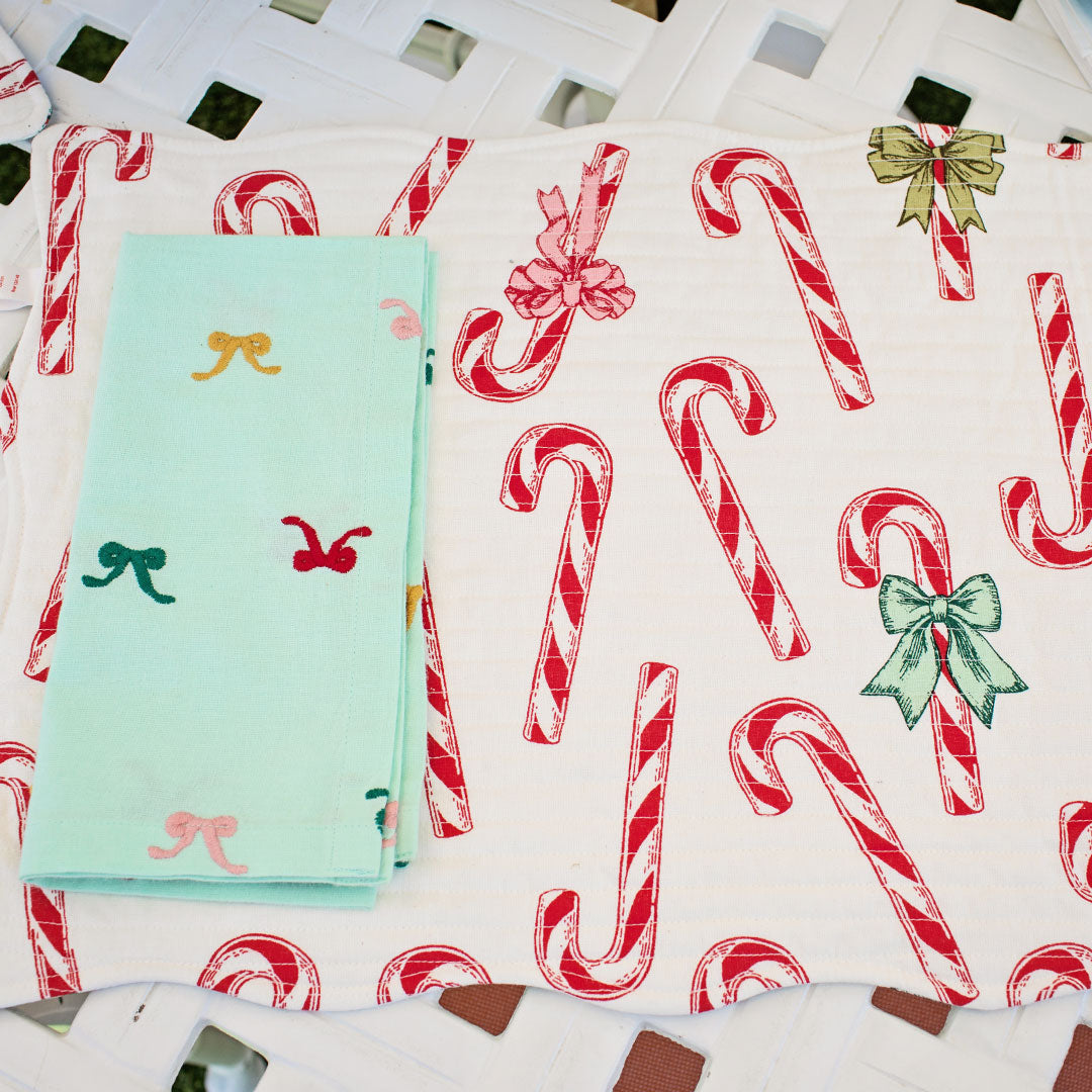 white quilted placemats with red candy cane print with bows
