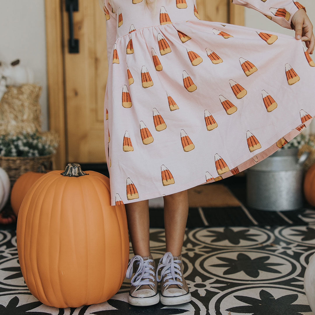 bottom half view of pink long sleeved dress with orange, yellow and white candy corn print