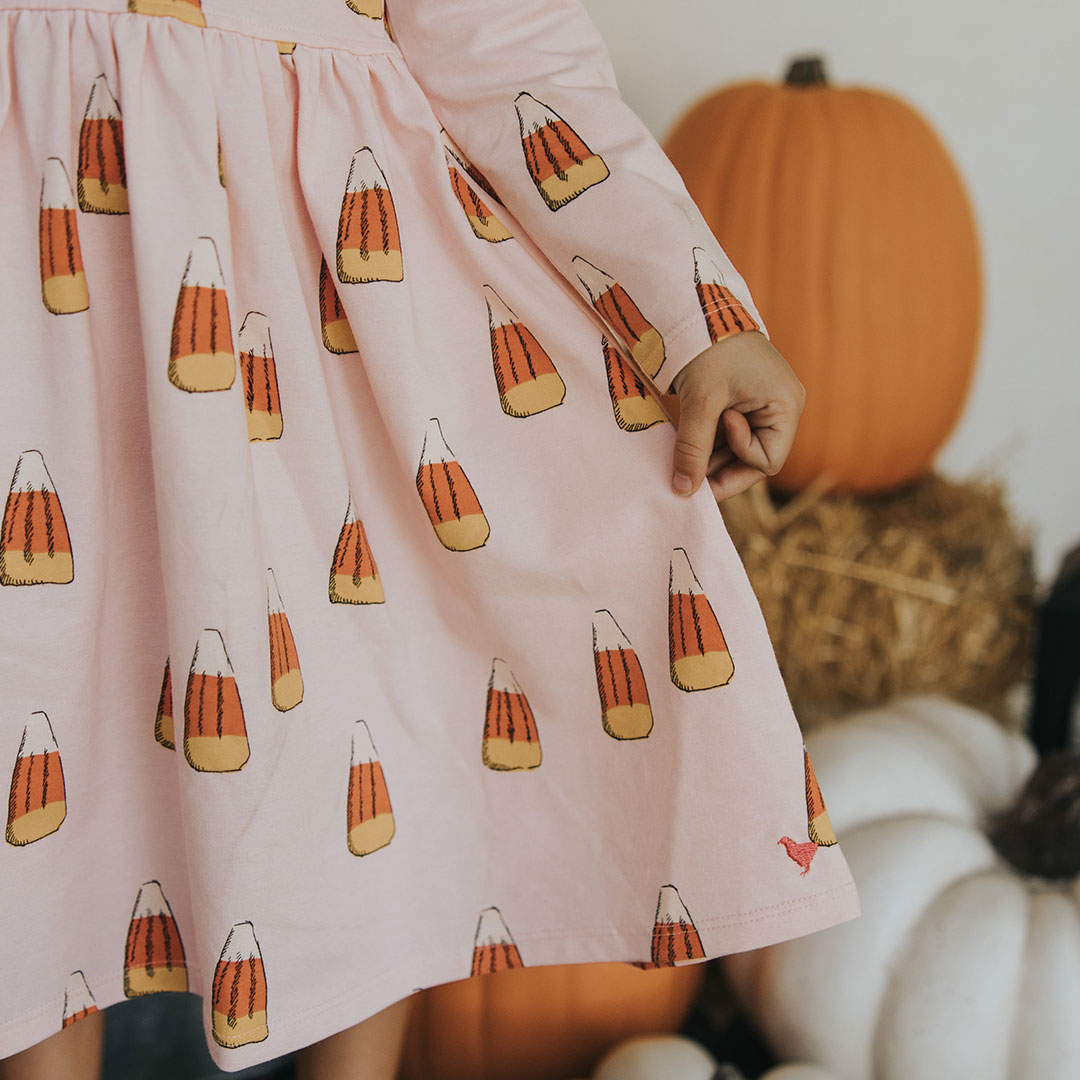 up close view of pink long sleeved dress with orange, yellow and white candy corn print