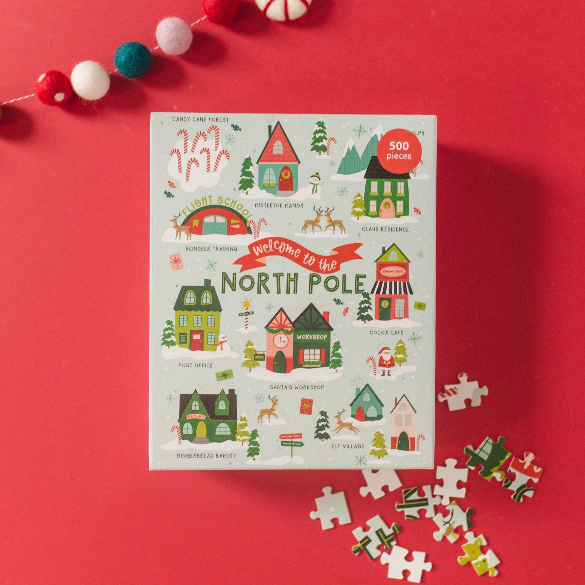 Pippi Post 500 piece Christmas puzzle box showing an illustrated North Pole village with Santa's workshop and loose puzzle pieces on a red background