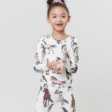 girl wearing white two piece loungewear set with multicolor horses