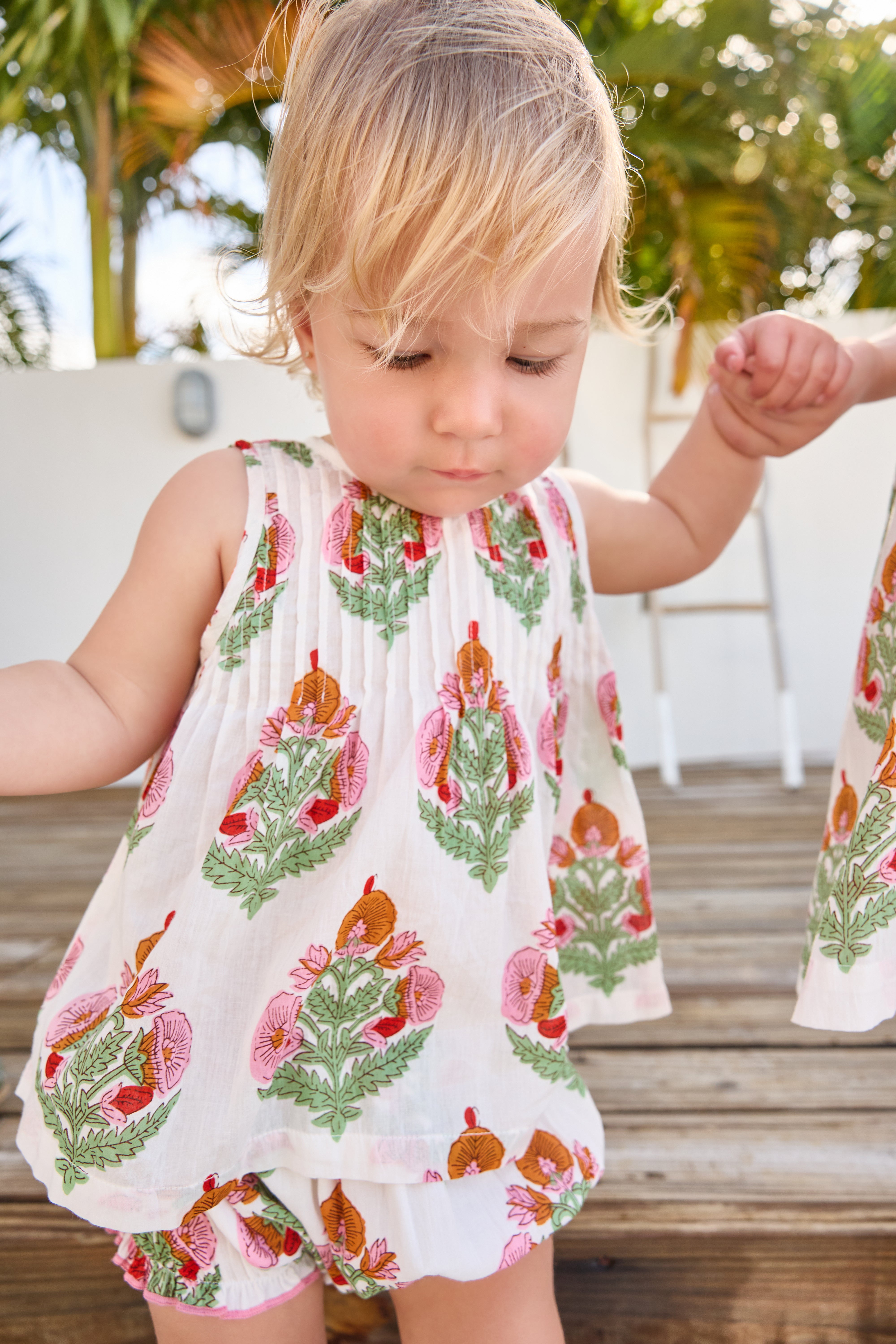 Child wearing a floral dress with a tropical setting in the background