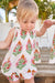 Child wearing a floral dress with a tropical setting in the background