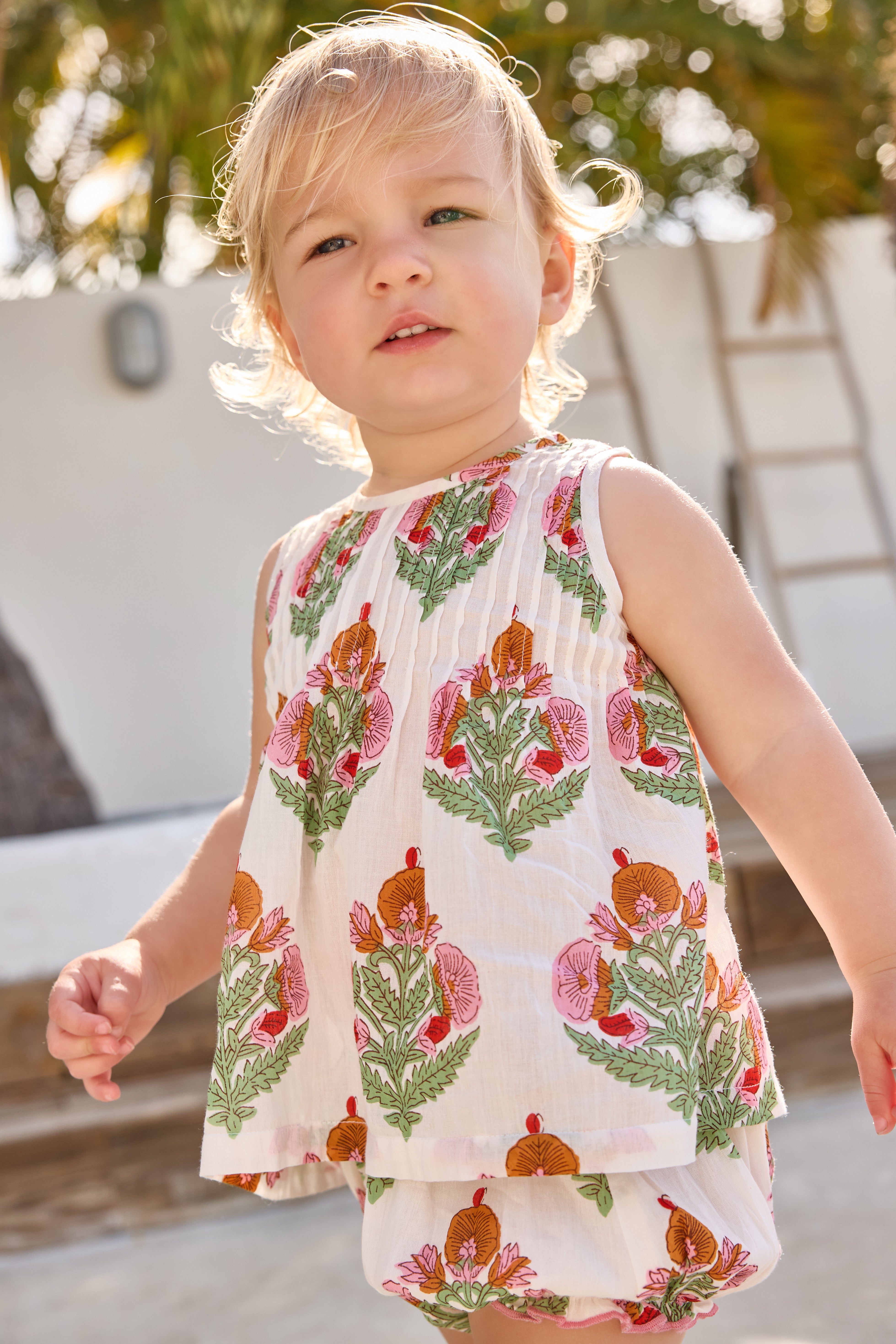 Child wearing a sleeveless top and shorts with floral pattern outdoors