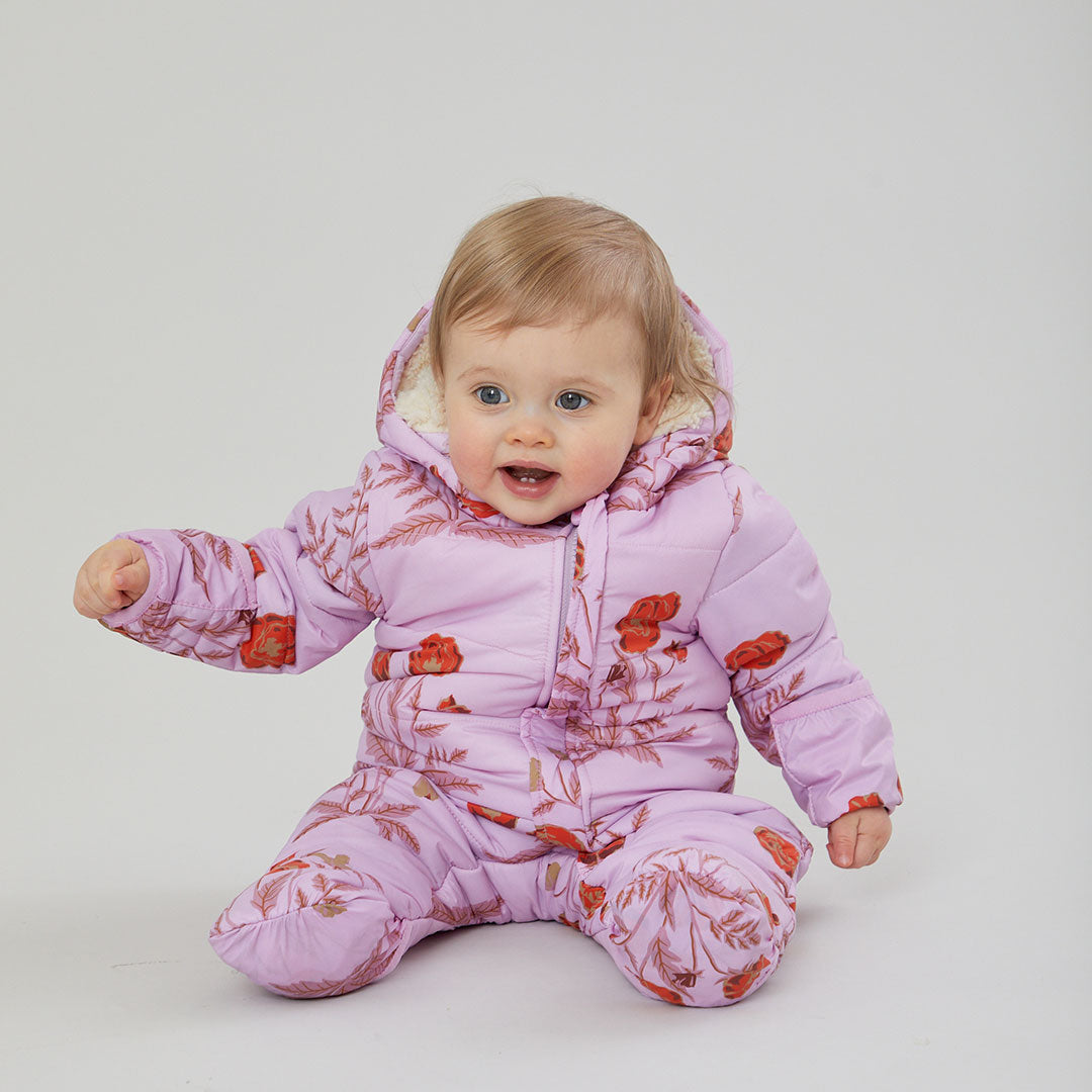 baby girl sitting up wearing lavender purple snowsuit with orange poppy flowers and fleece lining