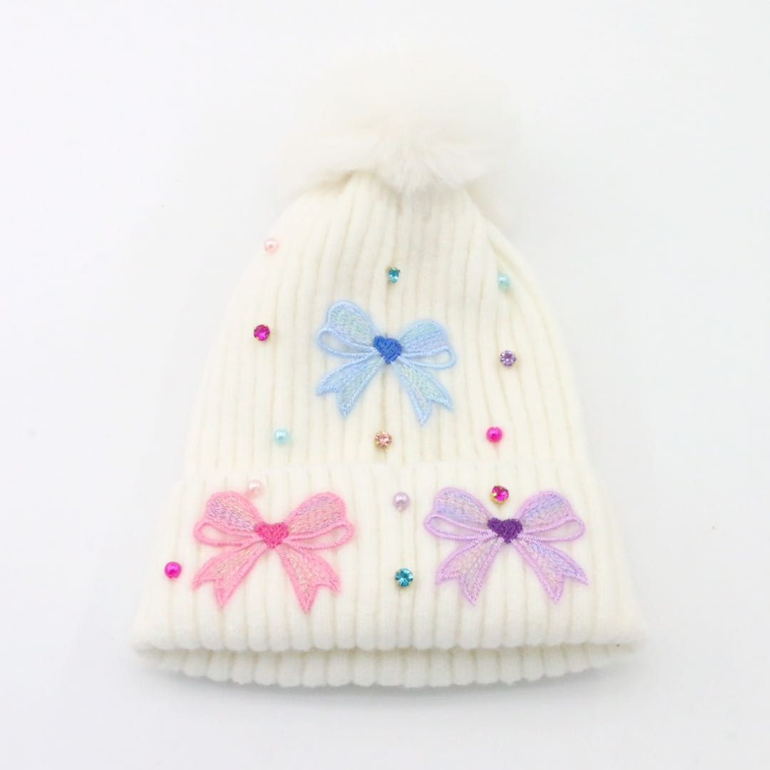 White knit beanie with colorful bow decorations on a white background