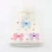 White knit beanie with colorful bow decorations on a white background